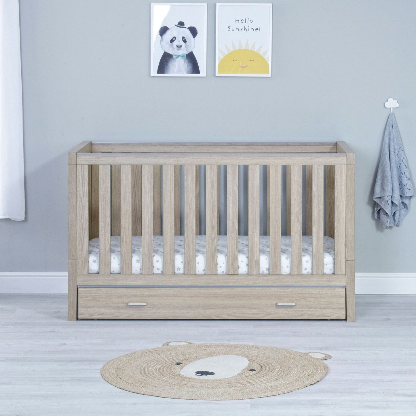 Babymore-Luno-Cot-Bed-with-drawer-oak-in-nursery-setting-as-cot-front